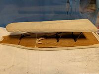 Top view of tabletop ironing board folded with cream cover and visible tear