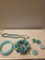 All jewelry items laid out: necklace, bangle, brooch, two earring pairs