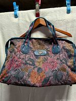 Front view of Riviera floral tapestry handbag showing handles, pattern and logo plaque