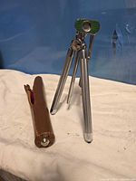 Tripod standing next to brown zippered case