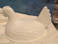 Side view of white milk glass hen lid showing feather detail