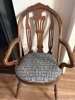 Front view of carved wood armchair with cushion on seat