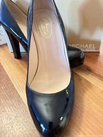 Front view of both pumps showing patent leather finish and round toe