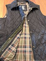 Vest front opened showing plaid lining, zip and snaps