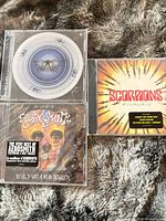 All three jewel case CDs—two Aerosmith titles and one Scorpions—arranged on surface