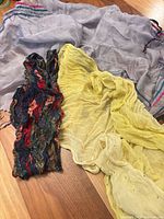 All three scarves laid out: yellow, light gray with stripes, multicolor abstract print