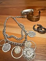 Overview of necklace, two cuff bracelets and pair hoop earrings on wood surface