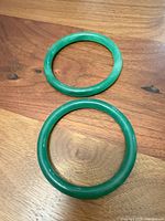 Pair of green stone bangles on wooden surface