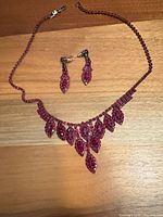 Full view red rhinestone necklace and earrings set on wood background