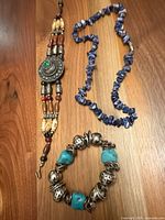 All three jewellery items laid out: multi-strand medallion bracelet, blue stone chip necklace, turquoise-look stretch bracelet