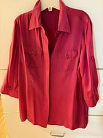 Front view of fuchsia silk blouse hanging on hanger