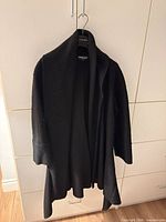 Front view of black open-front wrap coat on hanger