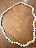 Full view of pearl necklace laid out in oval showing clasp and entire strand