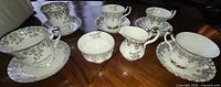Full view of five cup and saucer sets with creamer and sugar bowl