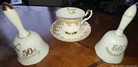 Front view of teacup, saucer, and two bells