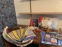 Overview of yarn bag, books, needles, oven mitts, doily, stuffed toy on desk