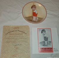 Front of plate with boy and dog image alongside certificate and card