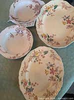 Four dishes showing fronts: two multicolour platters, two brown floral bowls