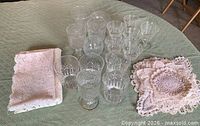 Group of clear glass cups with stacks of folded lace doilies