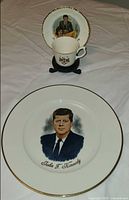 Plate, cup and saucer together displaying portraits and crest