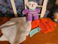 knitted bear, blanket, sweater, headband on wooden surface