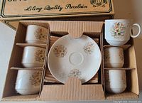 Open box showing five cups and one saucer in cardboard insert