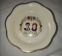 Top view of cream scalloped dish featuring portraits and crest