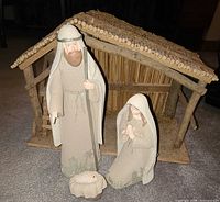 Full view of ceramic nativity figures in front of wood manger
