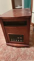 Front three-quarter view of wooden cabinet heater with vent and control panel