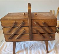 Closed wooden cantilever sewing box on legs