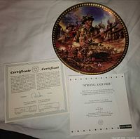 Front of porcelain plate with soldiers artwork and gold rim, certificate and insert visible