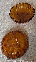 Pair of amber Indiana Glass bowls, one upright and one inverted showing underside pads and starburst