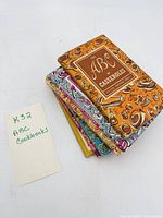 Stack of six slim illustrated cookbooks showing patterned covers