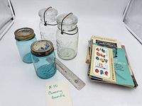 Group shot of four Ball jars, stack of pamphlets, ruler for scale
