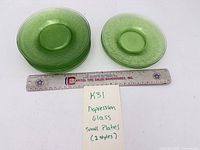 Stack of small green uranium glass plates with ruler for scale