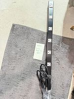 Full view of long black metal power strip with 12 outlets
