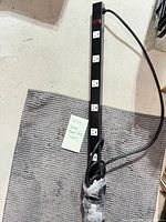 Full view of long black metal power strip showing outlets and cord