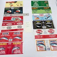 Group shot of 12 vintage unused salmon can labels laid out with ruler