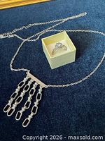 Necklace laid out showing chain, pendant tassel detail, and ring in box