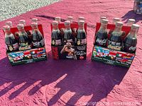 Three unopened Coca-Cola Atlanta 1996 Olympic Evander Holyfield 6-packs displayed on table