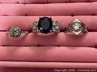 Three silver-tone rings lined in pink ring box