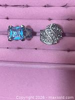 Two silver-tone rings: blue stone ring and clear pavé cluster ring