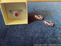 Ring in box alongside pair of hoop earrings on fabric background