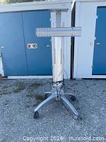Front view of cart showing base, vertical column, horizontal mounting bracket, cables at base