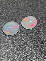 Pair of oval crystal jelly opals on black background showing play of color