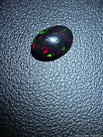 Top view of oval cabochon displaying red and green flashes