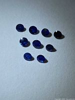 Nine round royal blue sapphires on light background