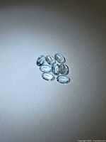 Group of eight light blue oval faceted gemstones on neutral background