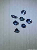 All seven faceted Tanzanite stones on neutral background