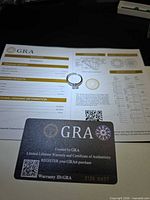 Ring on top of GRA documents showing grading report and warranty card